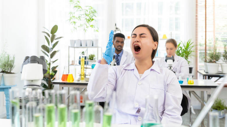 Des scientifiques féminines bâillant en laboratoire, des collègues derrière elle