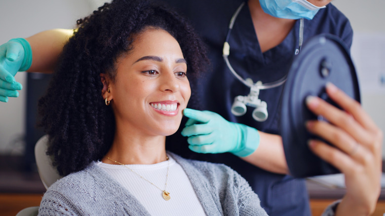 Femme regardant dans un miroir pendant que le dentiste montre la bouche