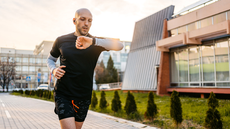 Homme regardant une montre de fitness tout en faisant de l'exercice à l'extérieur