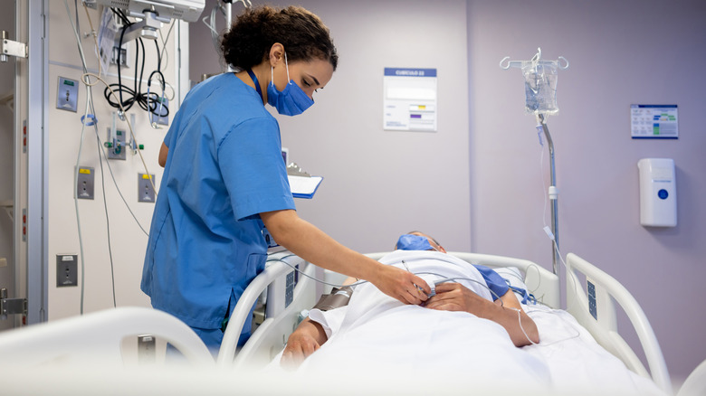 Infirmière vérifiant un homme dans un lit d'hôpital