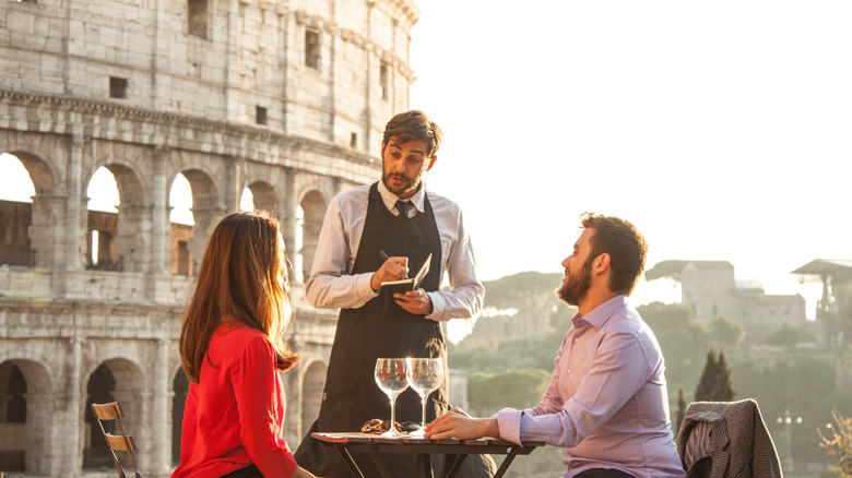 Couple commandant de la nourriture auprès du serveur au restaurant à côté du Colisée à Rome