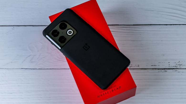 Un smartphone OnePlus 10 face cachée sur sa boîte sur une surface en bois