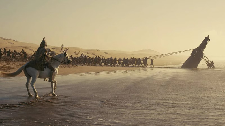 Des hommes tirant le cheval de Troie d'une plage dans L'Odyssée (2026)