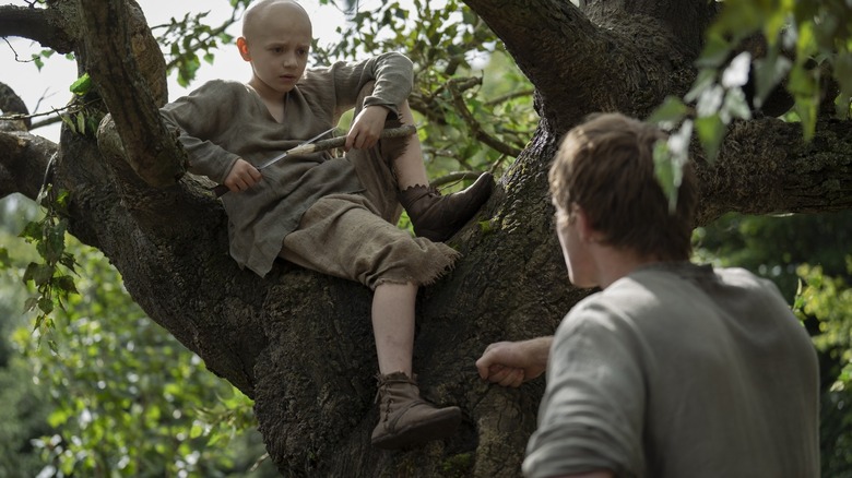 Dexter Sol Ansell dans le rôle d'Oeuf assis dans un arbre et regardant Peter Claffey dans le rôle de Ser Duncan le Grand dans Un Chevalier des Sept Royaumes
