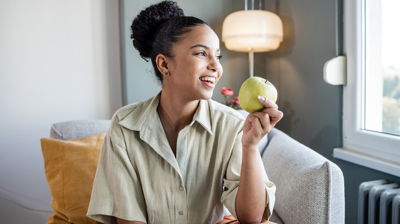 Femme tenant une pomme verte alors qu'elle était assise sur un canapé
