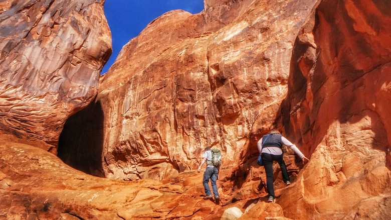 Randonneurs près de falaises abruptes dans la section Fiery Furnace du parc national des Arches dans l'Utah