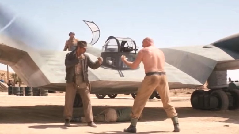 Indiana Jones de Harrison Ford affronte le mécanicien allemand de Pat Roach à côté d'un avion dans Les Aventuriers de l'arche perdue