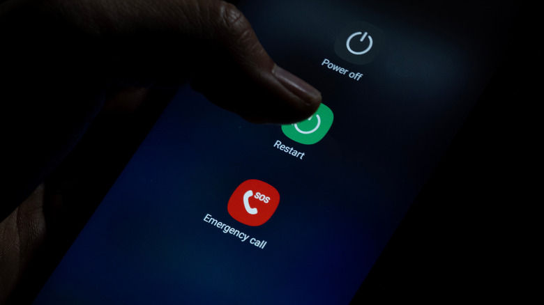 personne appuyant sur l'option de redémarrage dans le menu d'alimentation d'un smartphone