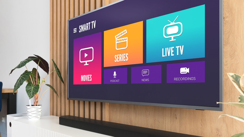 Smart TV montée sur un mur en bois avec une barre de son et une plante placée en dessous