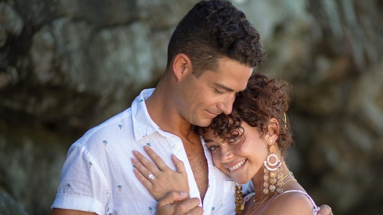 Wells Adams dans une chemise blanche boutonnée regarde Sarah Hyland pendant qu'ils s'embrassent