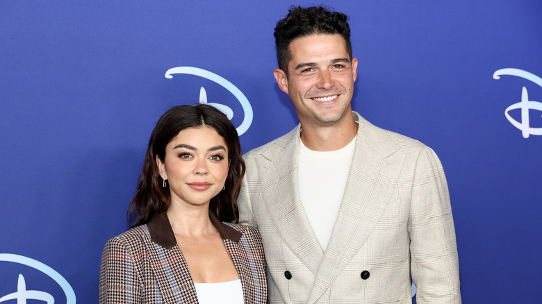 Sarah Hyland dans un blazer à carreaux marron posant à côté de Wells Adams dans un blazer crème