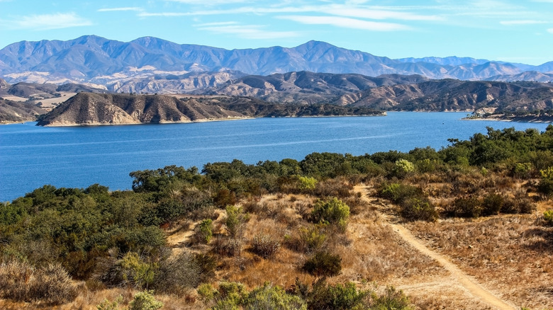 Paysage de la zone de loisirs du lac Cachuma avec broussailles et montagnes entourant l'eau