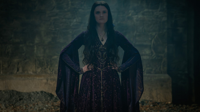 Gayle Rankin dans le rôle d'Alys Rivers debout devant un mur de pierre, les mains sur les hanches dans House of the Dragon