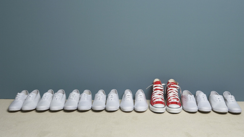 Une paire de chaussures rouges dans une rangée de chaussures blanches.