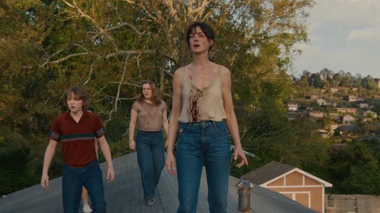 Anne Hathaway dans le rôle de Denise Platt avec Christian Convery dans le rôle de Brian Platt et Maisy Stella dans le rôle d'Audrey Platt debout derrière elle sur le toit dans The End of Oak Strett