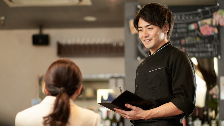 Un homme asiatique prenant une commande dans un restaurant.