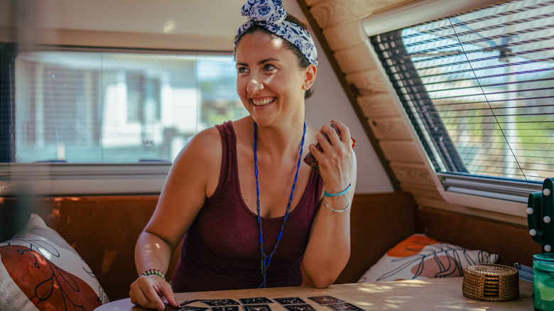 Une femme souriante assise dans la cuisine d'un camping-car, posant des cartes de divination
