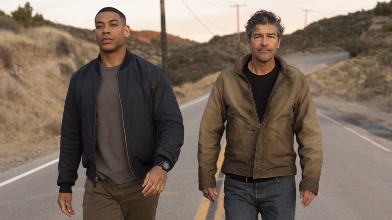 Kyle Chandler dans le rôle de Hal Jordan marchant à côté d'Aaron Pierre dans le rôle de John Stewart sur une route poussiéreuse dans Lanterns