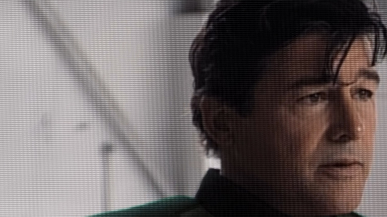Kyle Chandler dans le rôle de Hal Stewart portant un costume de super-héros vert et faisant une interview à la télévision dans Lanterns