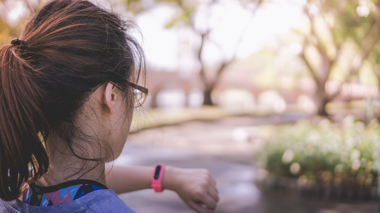 Femme vérifiant une montre intelligente tout en faisant de l'exercice à l'extérieur