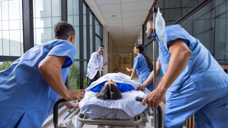 Une femme sur une civière est transportée d'urgence par le personnel de l'hôpital dans un couloir.