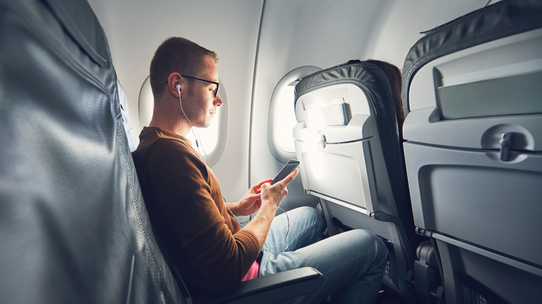 Un homme utilise son téléphone dans un avion.