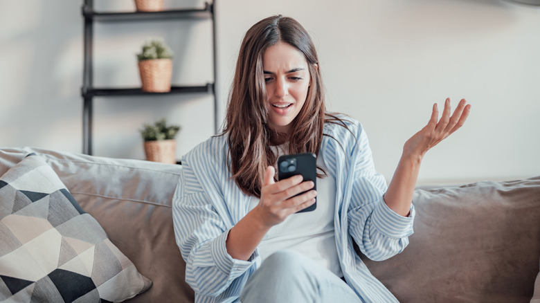 Une femme regardant son téléphone avec exaspération