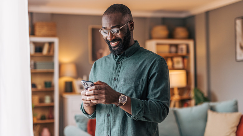 Un homme tenant un smartphone en souriant