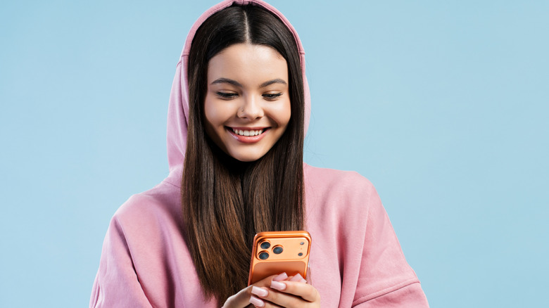 Une fille portant un sweat à capuche et tenant un smartphone