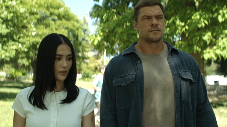 Lila Hoth d'Agnez Mo marche aux côtés de Jack Reacher d'Alan Ritchson dans un parc à Reacher