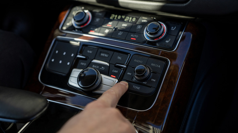 Une personne utilisant sa console centrale pour contrôler la lecture audio à l'intérieur de sa voiture