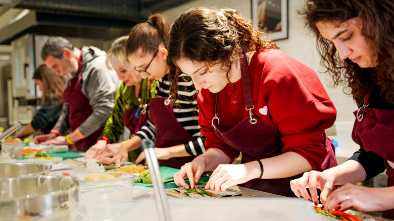 Groupe de personnes se concentrant pendant qu'elles préparent des sushis