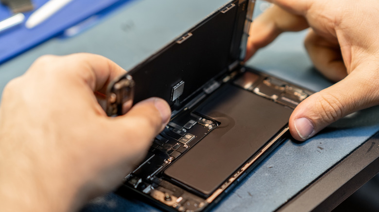 Une personne réparant un smartphone en ouvrant l'écran.