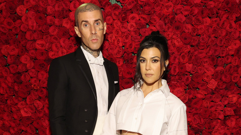 Travis Barker et Kourtney Kardashian posent devant un mur de roses rouges