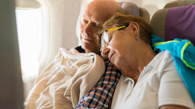 couple de personnes âgées dormant dans un avion