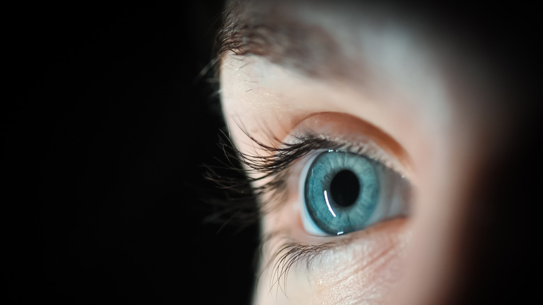 Gros plan de l'oeil bleu dans l'obscurité