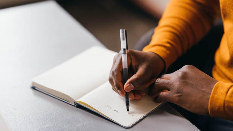 Personne écrivant des mots dans un cahier