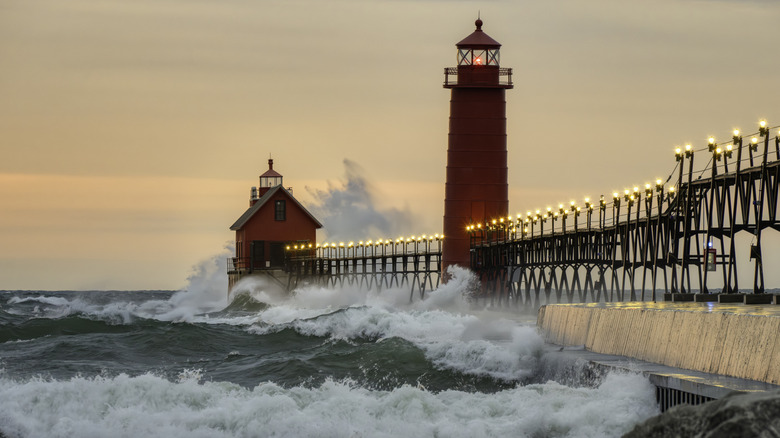 Vagues frappant la jetée éclairée avec deux phares du parc national de Grand Haven au crépuscule.