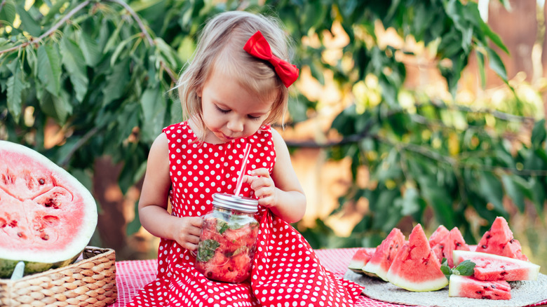 Un enfant mignon mange de la pastèque mûre et juteuse en été. Enfant, bébé, collation saine pour les enfants. Adorable petite fille essayant de vendre de la limonade
