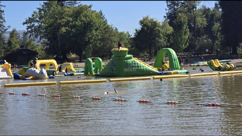 Les enfants nagent et jouent dans le parc aquatique gonflable du parc régional de Spring Lake.