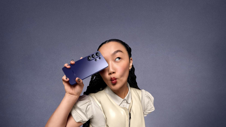 Une fille tenant le Samsung S26 Ultra sur un fond gris de studio