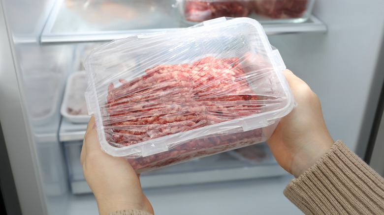 Personne sortant de la viande d'un réfrigérateur
