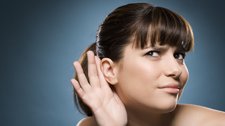 Personne qui écoute avec la main derrière l'oreille