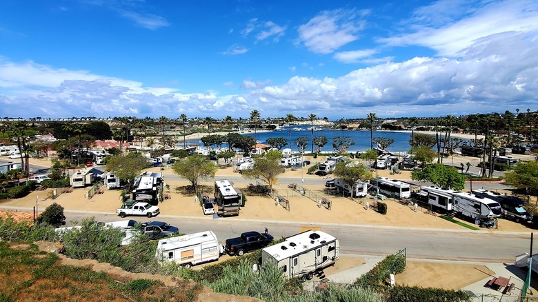 Une vue aérienne du Newport Dunes Waterfront Resort & Marina avec des camping-cars, des paysages désertiques et un lac.