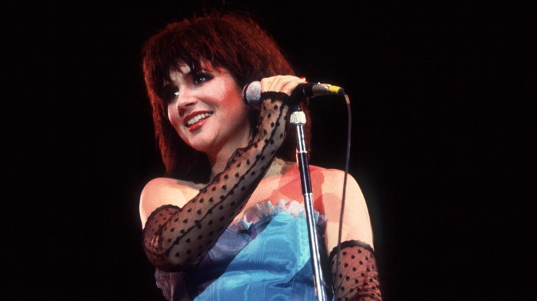 Linda Ronstadt portant un haut bustier bleu et des mitaines transparentes lors d'un spectacle dans les années 80
