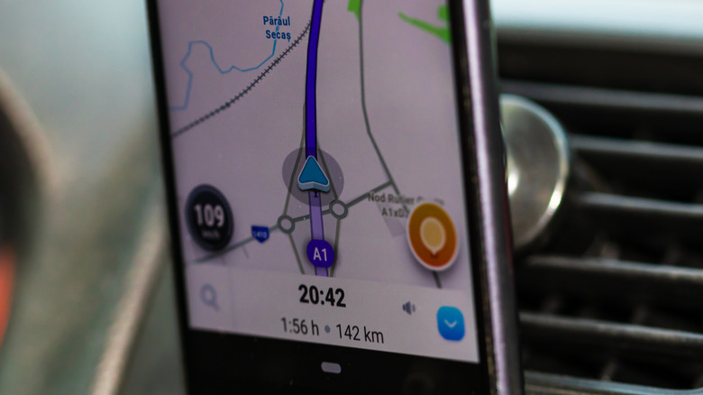 Une image en gros plan de l'application Waze sur un téléphone sur le tableau de bord d'une voiture