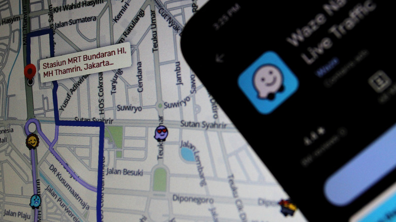 Logo de l'application Waze affiché sur un téléphone mobile avec une carte en arrière-plan