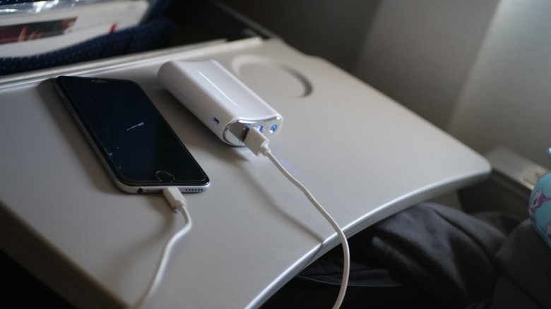 Un chargeur portable et un téléphone sur une table-plateau.