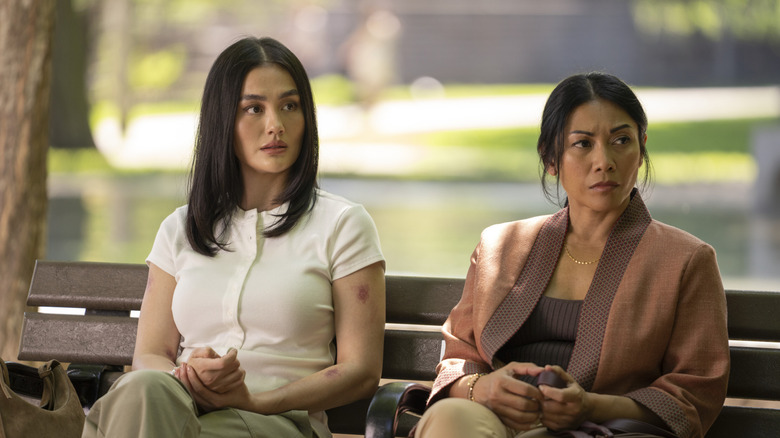 Agnez Mo dans le rôle de Lila Hoth assise sur un banc de parc à côté d'Anggun dans le rôle d'Amisha dans Reacher