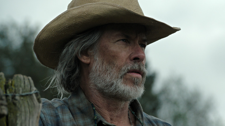 Un gros plan de Guy Pearce dans le rôle de Pops debout près d'une clôture dans The Dog Stars
